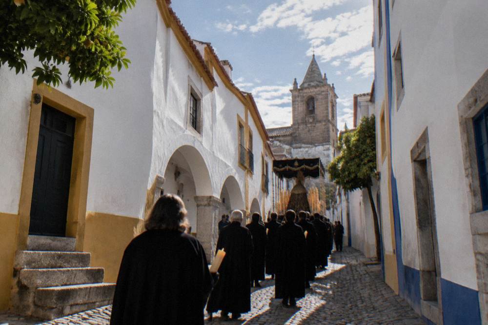 Candle-lit religious procession moving through a narrow medieval street in Évora