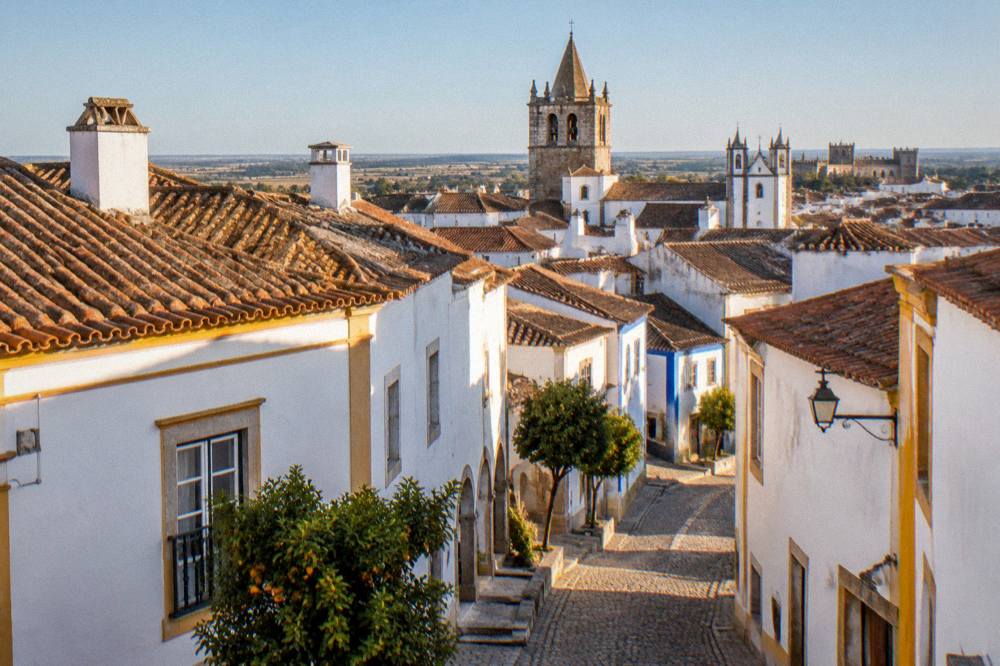 A rooftop view over Évora's old town at golden hour with church towers