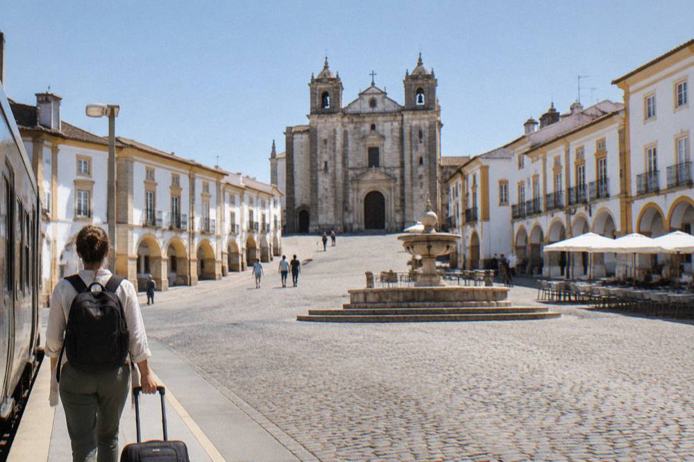 A traveller stepping off a regional train onto a small station platform in the Alentejo countryside