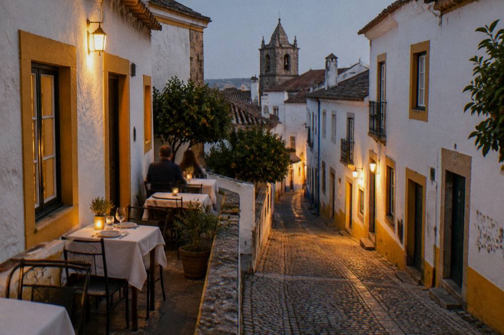An evening table outside a whitewashed restaurant in a narrow lit street of Évora's old town