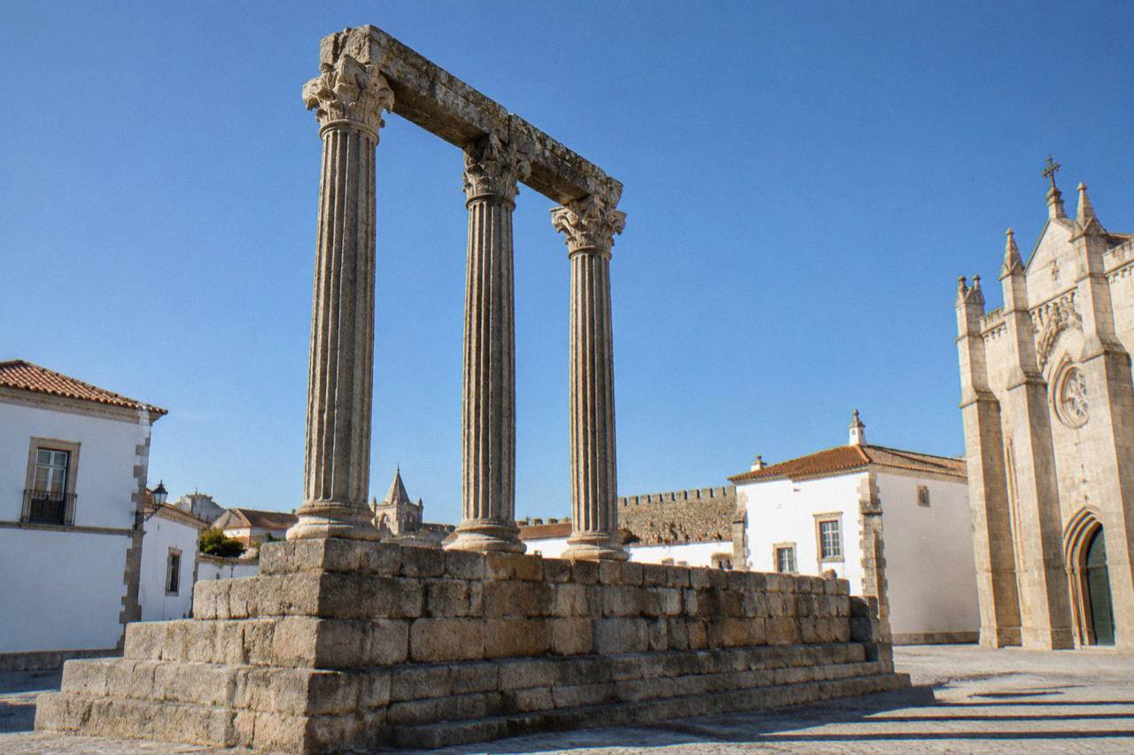 The Roman temple columns and historic rooftops of Évora seen in late afternoon light