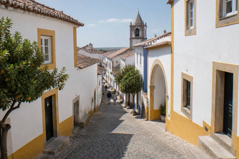 A shaded cobbled street in Évora's old town with whitewashed walls and warm daylight