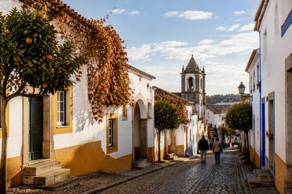 The bell tower and rooftops of Évora under a wide autumn sky with scattered clouds