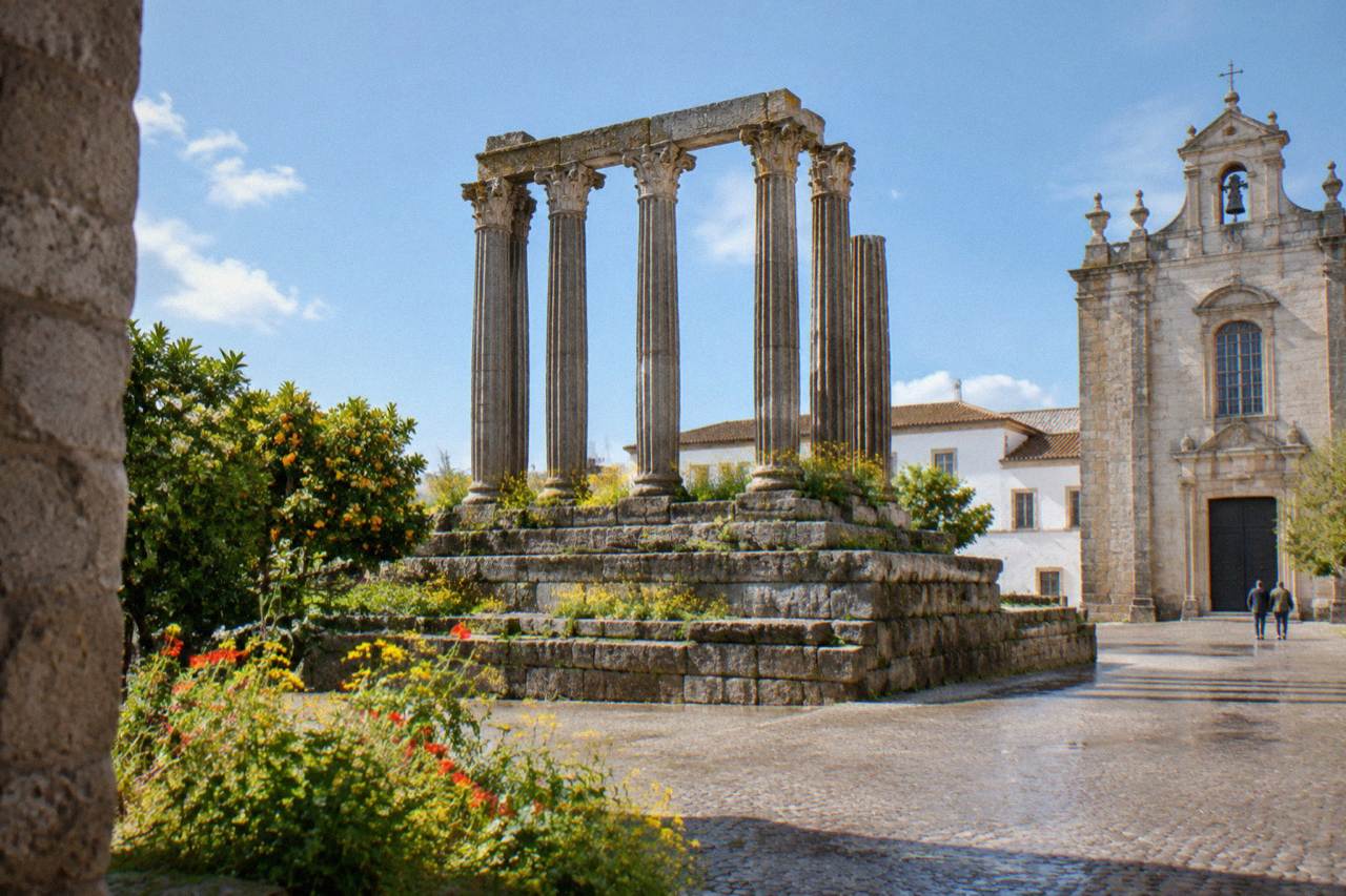 Spring morning light on the Templo Romano in Évora with wildflowers growing between the ancient stone columns