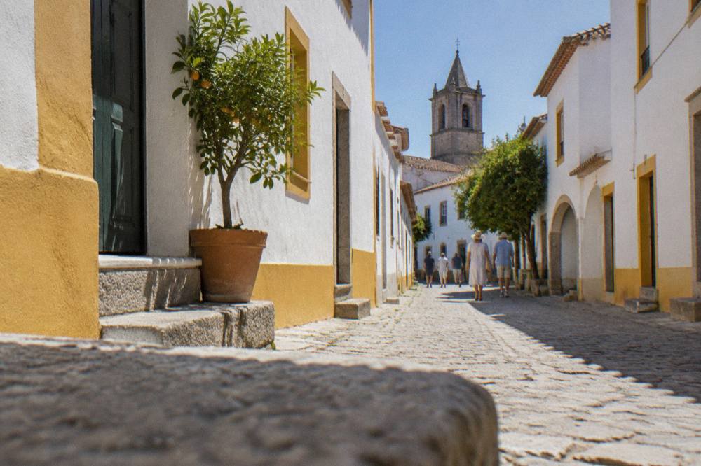 Narrow white street in Évora with strong shadows under a midday summer sun