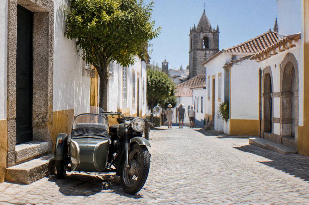 Vintage motorcycle sidecar parked on a cobbled street beside old stone buildings