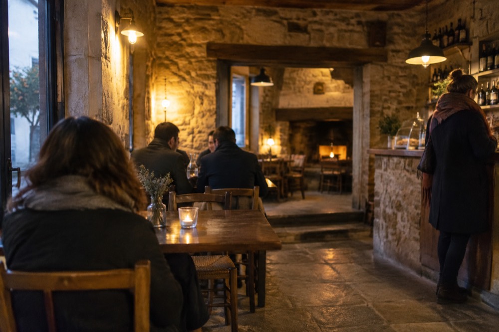 A warm-lit tavern interior in Évora's old town on a winter evening, with stone walls and a small counter