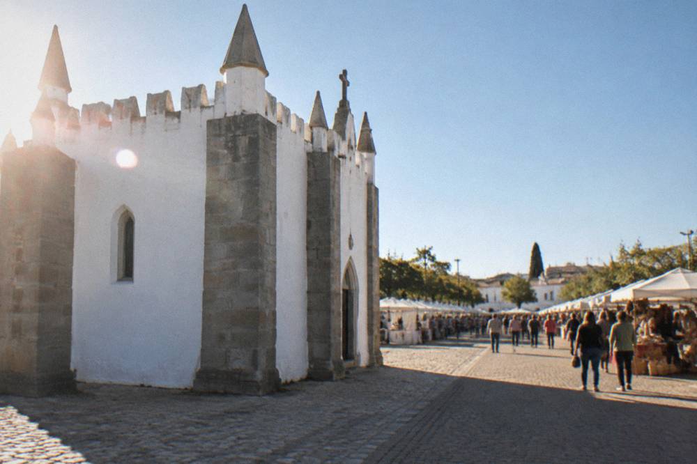 A lively outdoor fair with rows of stalls and crowds on the Rossio de São Brás in Évora