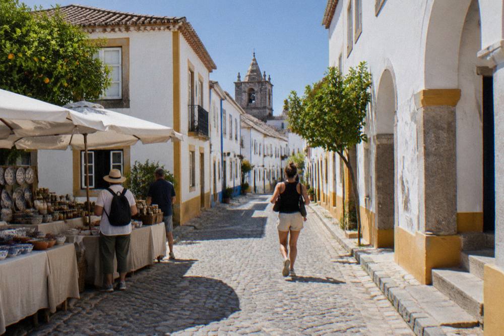 Visitors browsing an open-air stall of ceramics and regional food jars in Évora