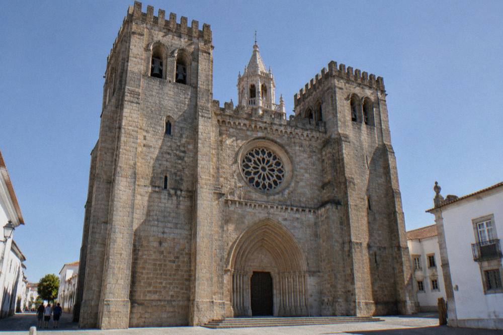 Stone facade of the Évora cathedral with its rose window and twin towers