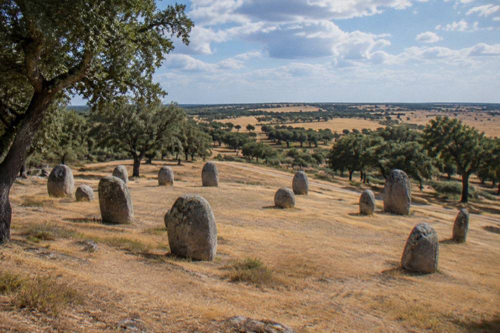 Standing stones of the Almendres cromlech on a grassy hillside near Évora