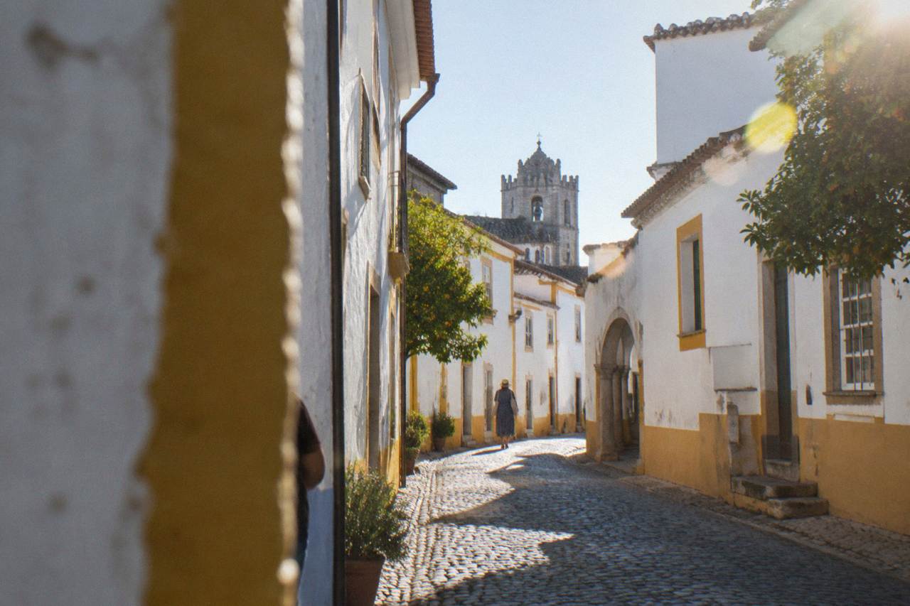 A narrow cobbled street inside the walled historic centre of Évora with whitewashed buildings