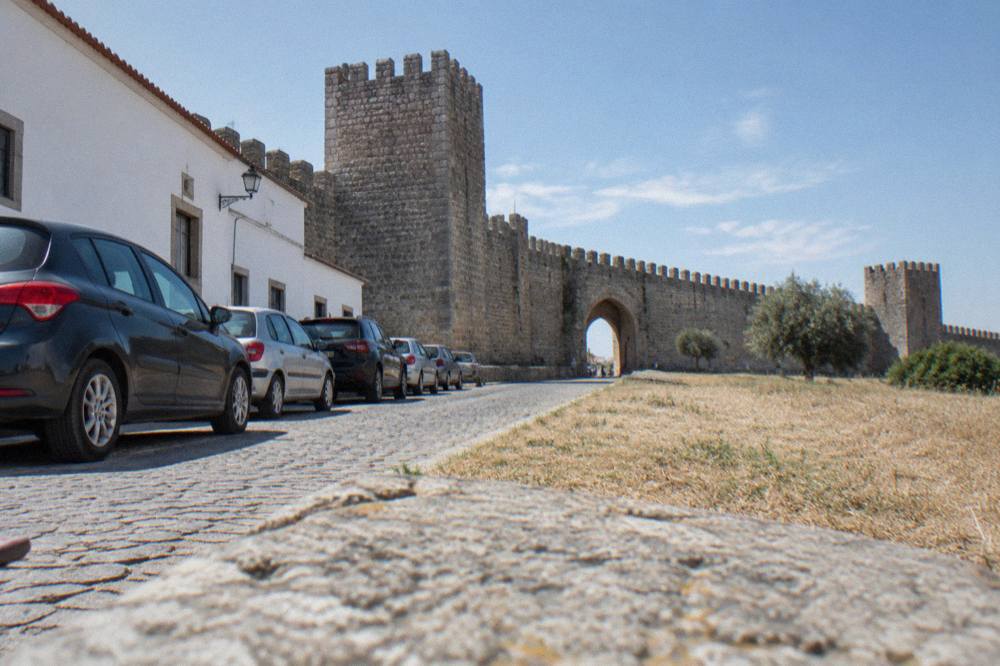 Parked cars along a street near the medieval walls of Évora in morning light