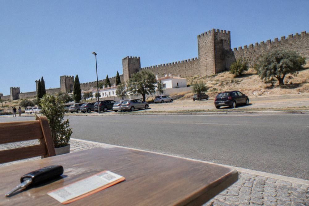 A rental car key and a rail ticket on a table beside a map of the Alentejo
