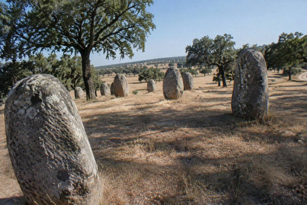 Standing stones of the Almendres cromlech on a grassy hillside near Évora