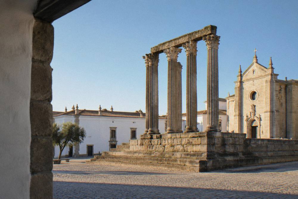 Granite columns of the Roman temple in Évora rising against a clear sky at golden hour
