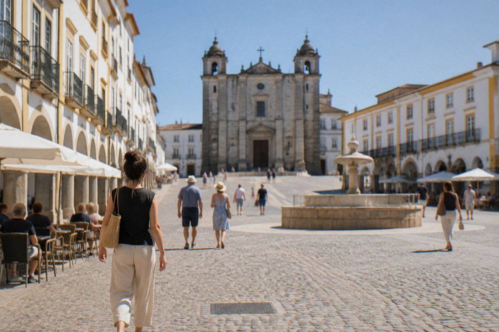 Locals and visitors walking across Praça do Giraldo in the morning light