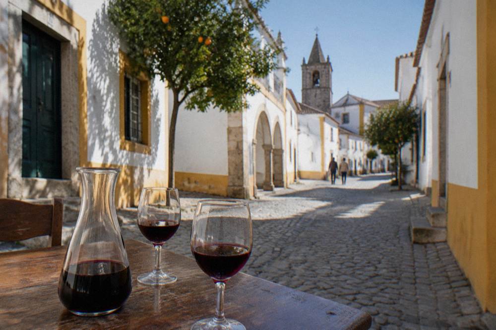 A carafe of red Alentejo wine and two glasses on a wooden tavern table