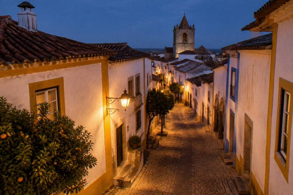 A hilltop Alentejo village street in warm evening light with stone houses