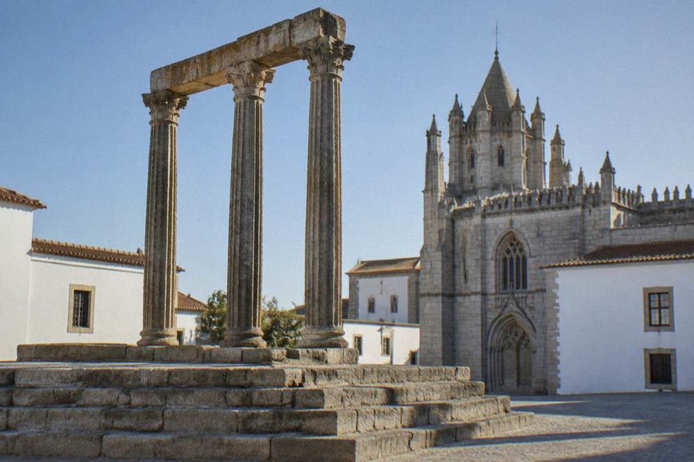 The Roman temple of Évora in early morning light with the cathedral behind it