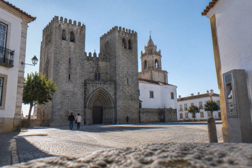 Stone ticket machine and entrance sign beside the gothic cathedral of Évora on a bright morning