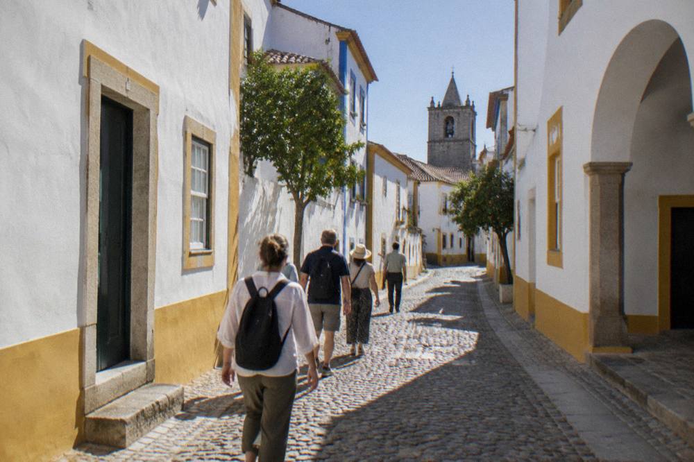 Small group of visitors following a guide on foot through a narrow white street of Évora
