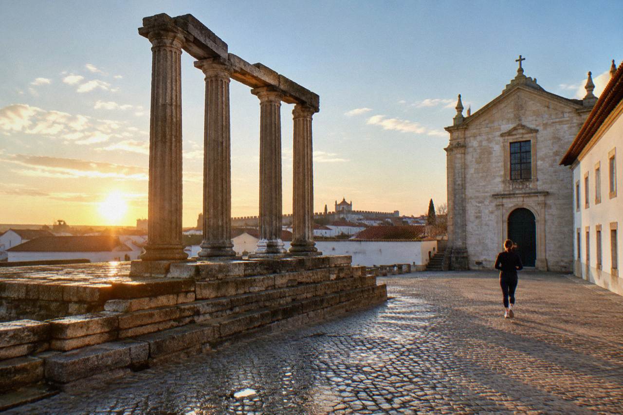 The walled historic centre of Évora seen at golden hour with the Templo Romano columns in the foreground