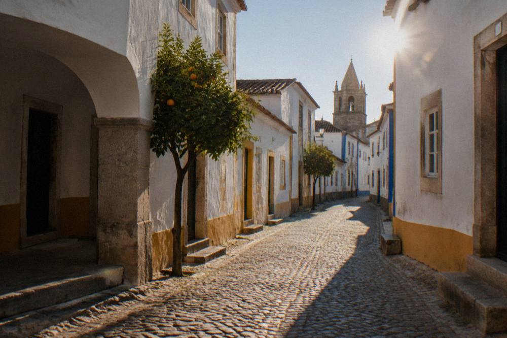Sunlight falling on an empty railway platform with white walls and a tiled roof in the Alentejo