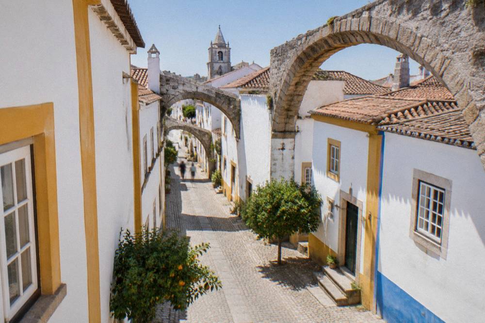 Stone arches of an old aqueduct running between whitewashed houses on the edge of Évora