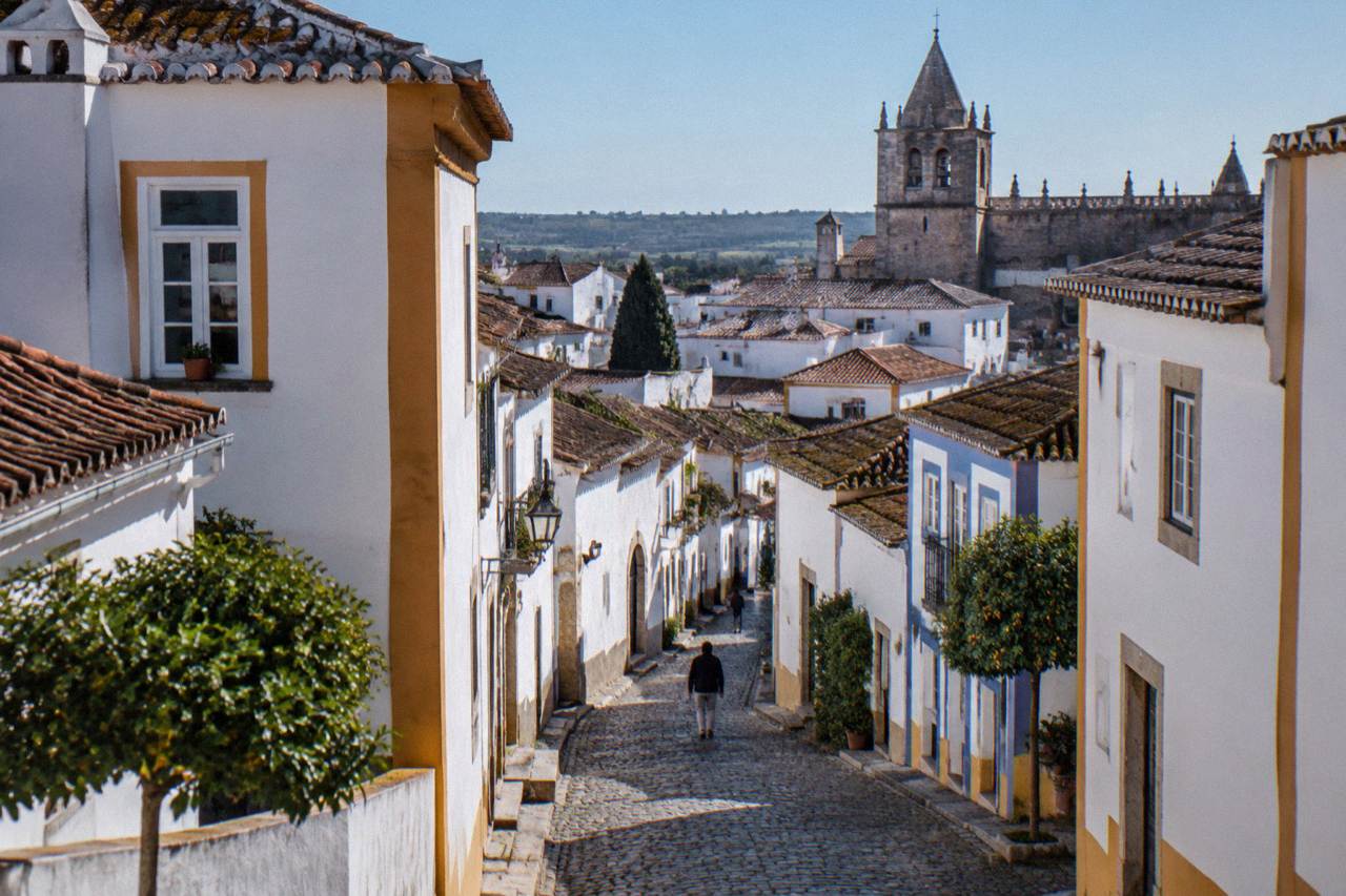 Golden historic buildings and a church tower inside the walled centre of Évora under a clear sky