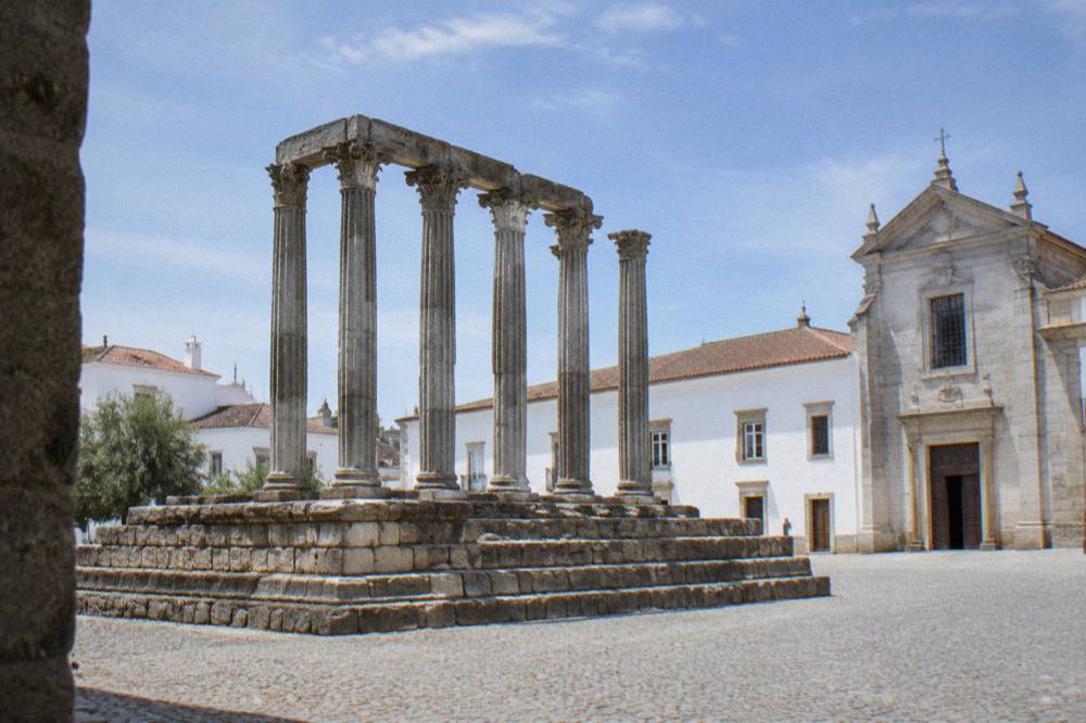 The Roman temple of Évora standing on a stone platform beside old white houses