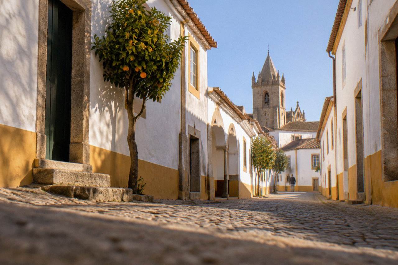 Golden limestone buildings and a church tower inside the walled historic centre of Évora under a clear sky