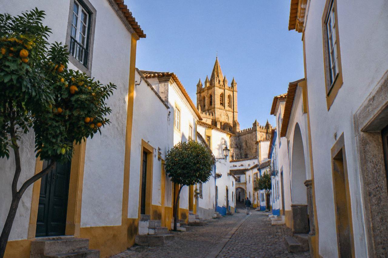 Golden late afternoon light on Évora's cathedral tower above whitewashed rooftops