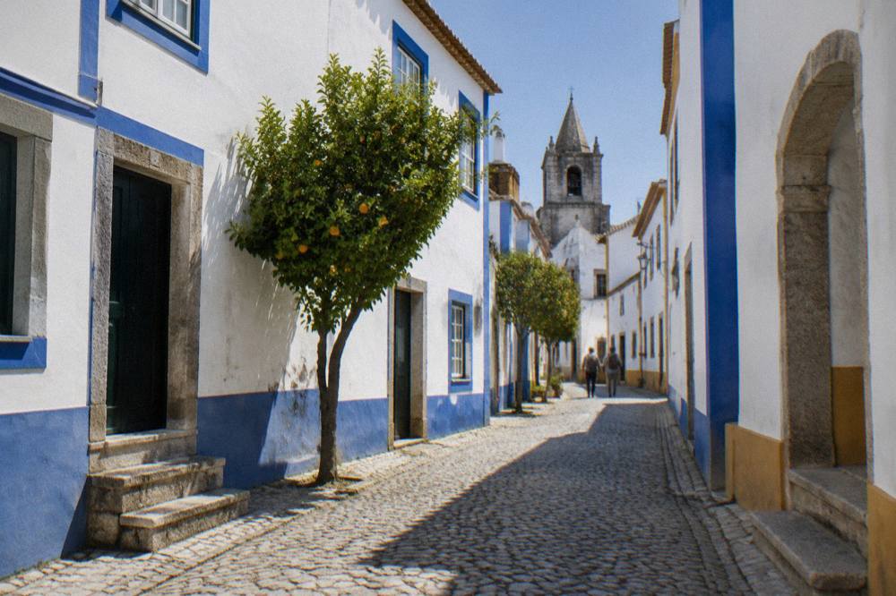 Narrow cobbled street in Évora's walled centre with white walls and blue trim