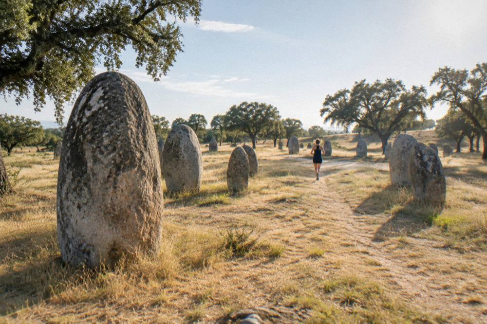 Standing stones of the Almendres cromlech scattered across a grassy Alentejo hillside