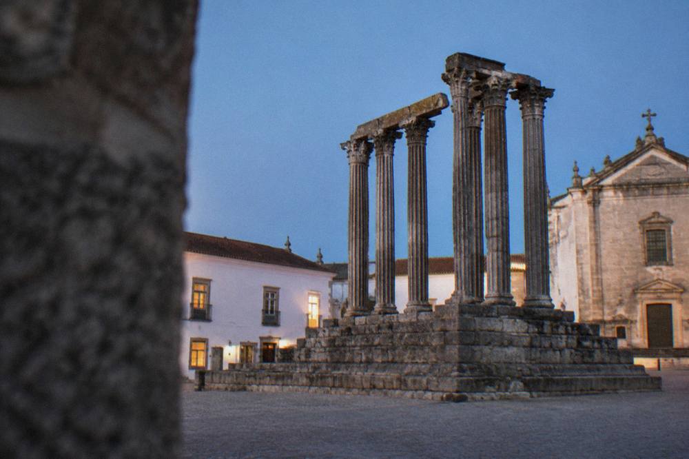 The Roman temple columns of Évora standing against a blue evening sky