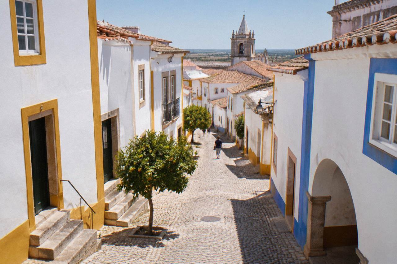 Golden limestone buildings and a church tower inside the walled historic centre of Évora under a clear sky