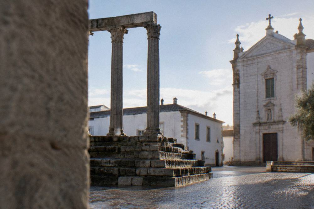 The Roman temple columns of the Templo Romano in Évora framed by limestone buildings