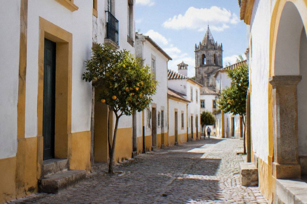 A quiet cobbled street of whitewashed houses with yellow trim in Évora's historic centre