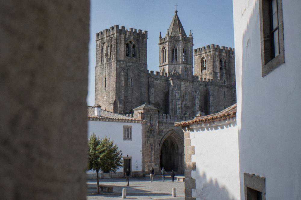 The stone arches and bell tower of Évora Cathedral seen from a narrow lane