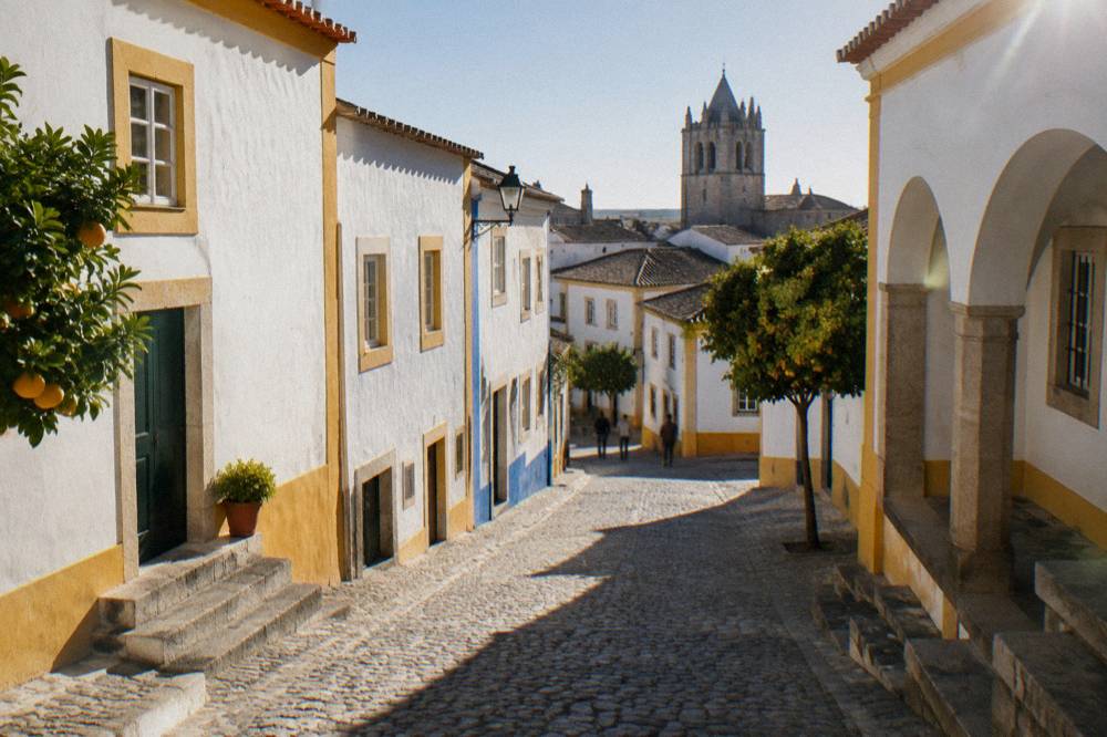 Sunlight falling across a limestone street in Évora with deep shadows at midday