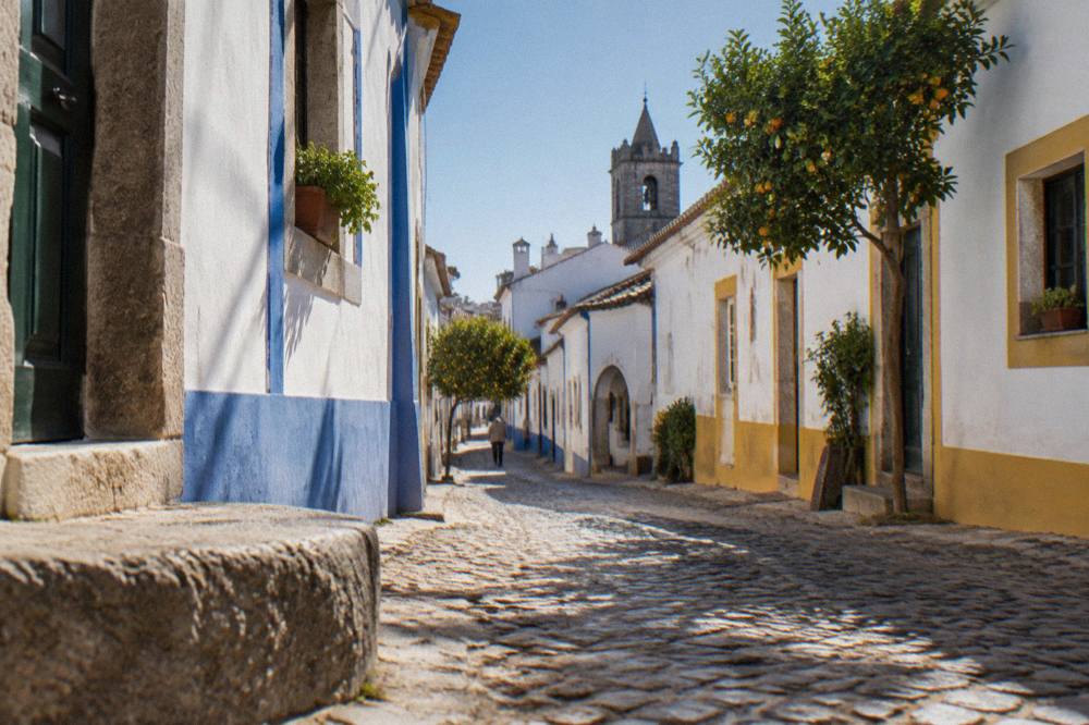 A narrow whitewashed street in Évora's historic centre with blue and yellow trim