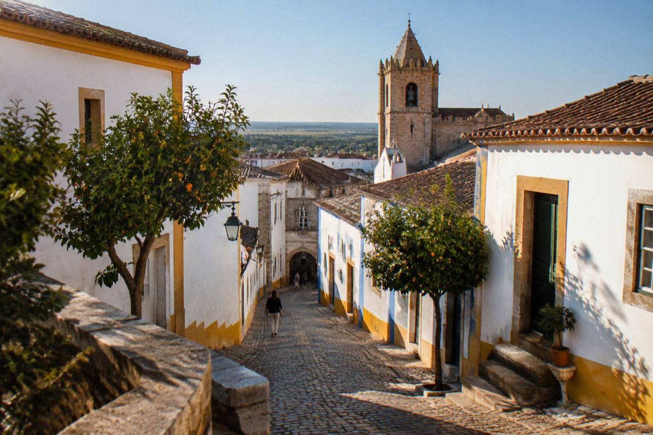 Golden stone buildings and a church tower under a blue sky in the historic centre of Évora