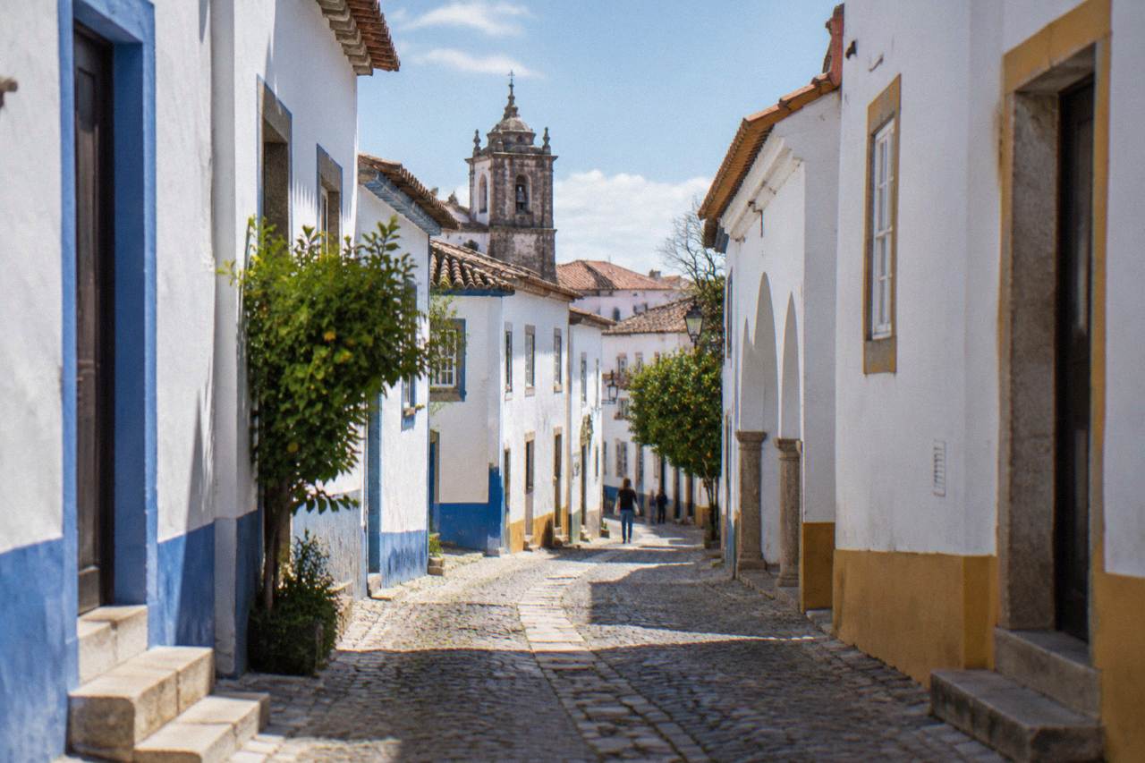 A narrow cobbled street in the historic centre of Évora with white-washed houses and blue trim