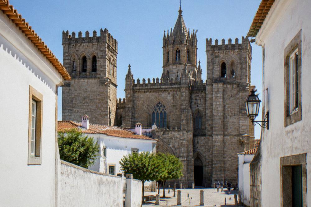 The Gothic cathedral of Évora seen from a narrow lane with white houses