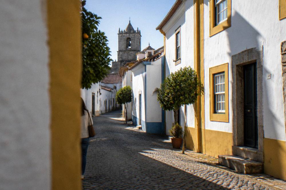 A shaded stone street in Évora with strong afternoon sunlight on white walls