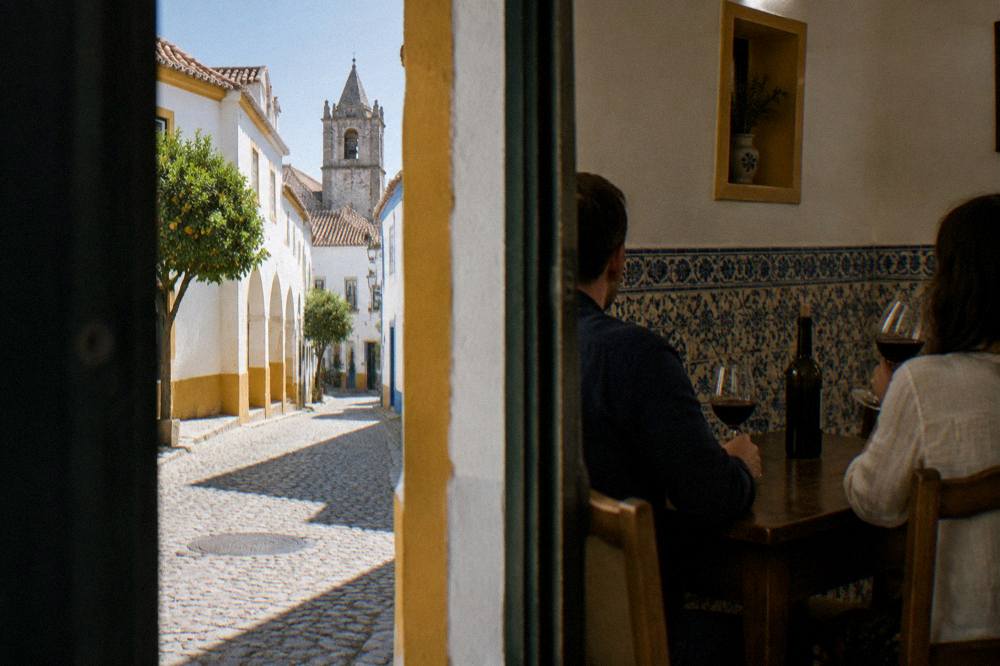 A couple tasting red Alentejo wine at a wooden table in a tiled room in Évora