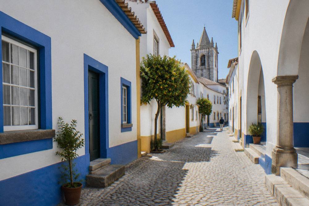 Narrow street in Évora with white walls and blue trim under strong midday light