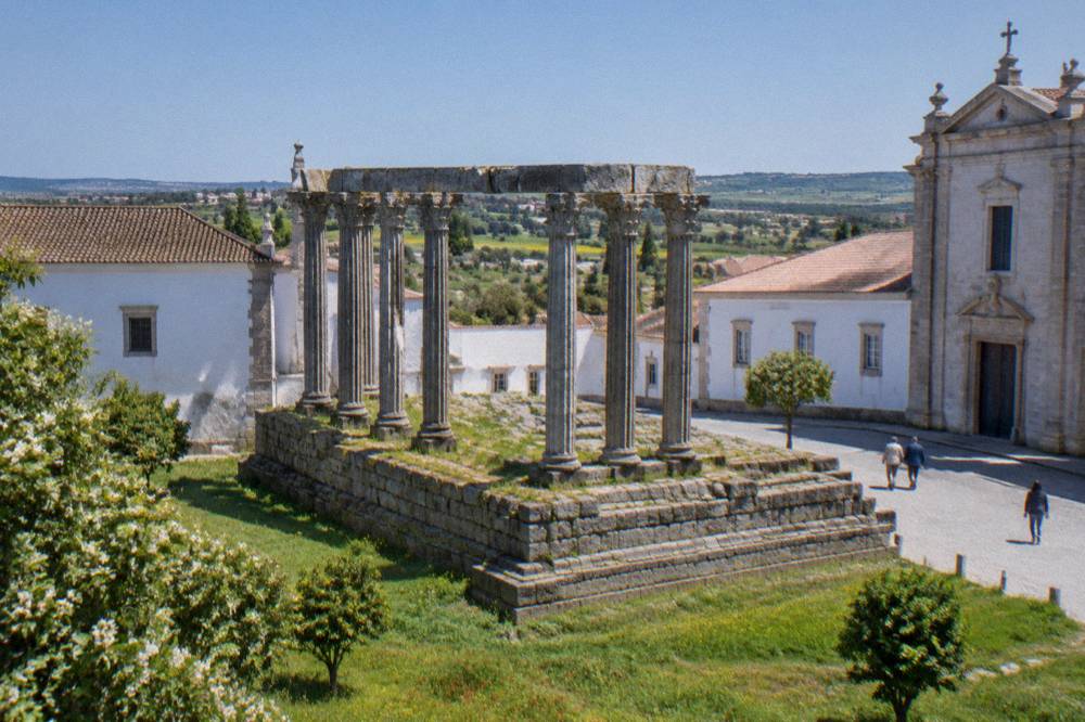 Spring light on the Roman temple columns in Évora with green grass around the base