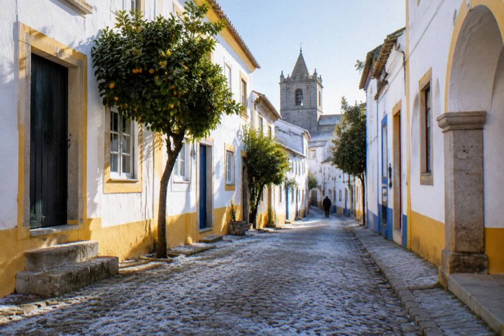 Frost on the ground of an early morning street in Évora with warm light on white walls